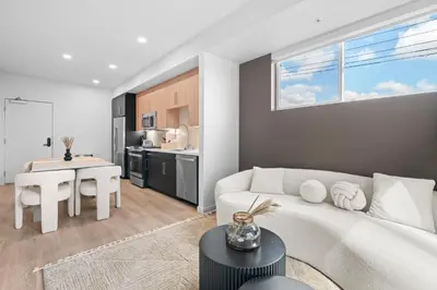 a living room with a white couch and a kitchen at Luxury & Modern Apt by the Grove in Los Angeles