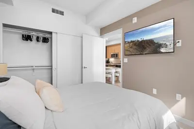 a bedroom with a white bed and a tv on the wall at Luxury & Modern Apt by the Grove in Los Angeles