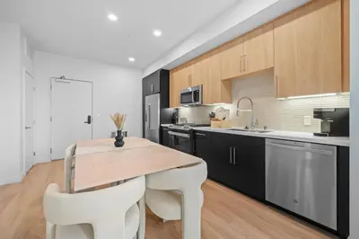a kitchen with a wooden table and white chairs at Luxury & Modern Apt by the Grove in Los Angeles