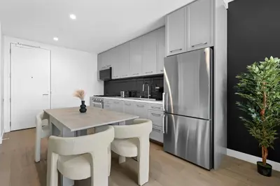 a kitchen with a table and a stainless steel refrigerator at Brand New Modern & Luxury Residence in DTLA in Los Angeles