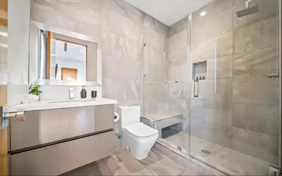 a bathroom with a toilet and a glass shower at Luxurious Retreat - Modern House with Pool in Los Angeles
