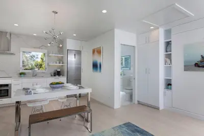 a white kitchen with a table and chairs in it at Elegant Ocean View Studio in Prime Santa Monica Location in Los Angeles