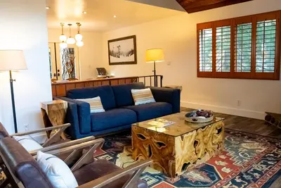 a living room with a blue couch and a table at The Mighty Pines Retreat + Large Patio + BBQ+View! in Lake Arrowhead