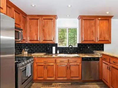 a kitchen with wooden cabinets and stainless steel appliances at The Mighty Pines Retreat + Large Patio + BBQ+View! in Lake Arrowhead