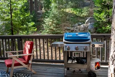 a grill and a chair on a deck at The Mighty Pines Retreat + Large Patio + BBQ+View! in Lake Arrowhead
