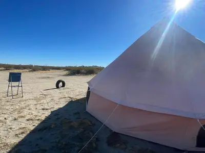 a tent and a chair on a beach at New Yurt City in Lake Los Angeles