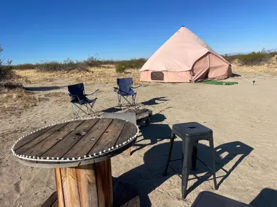 a table and two chairs and a tent on the beach at New Yurt City in Lake Los Angeles