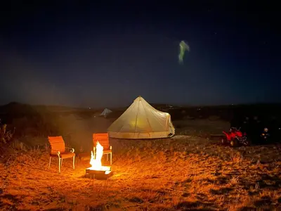 two chairs and a tent in the desert at night at New Yurt City in Lake Los Angeles