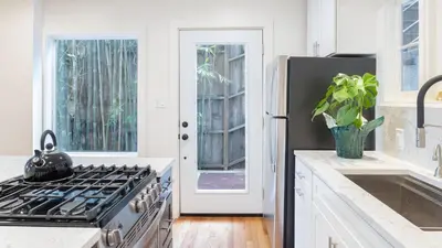 a white kitchen with a stove and a refrigerator at A-Lister by AvantStay Hollywood Hills Luxe Group Escape w Pool in Los Angeles