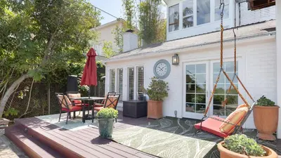 a patio with a table and chairs and a clock on a house at A-Lister by AvantStay Hollywood Hills Luxe Group Escape w Pool in Los Angeles