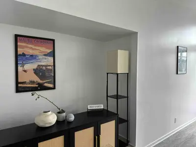 a living room with a black cabinet and a poster at 30 PCT OFF!! Limited Time! Malibu Ocean Wave with King Bed, Walking to Beach and Hiking in Malibu