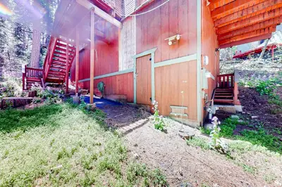 a red building with a red door and stairs on it at Hidden Wonder in Crestline