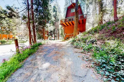 a red house sitting on a hill next to a road at Hidden Wonder in Crestline
