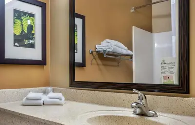 a bathroom with a sink with a mirror and towels at Relax Suites Extended Stay - La Mirada in La Mirada
