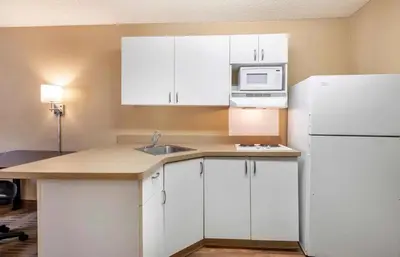 a kitchen with white cabinets and a sink and a refrigerator at Relax Suites Extended Stay - La Mirada in La Mirada