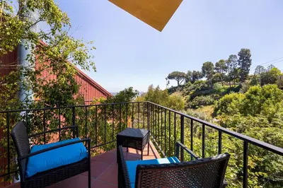 a balcony with two chairs and a view of a hill at Hollywood Hills Retreat w Sweeping Views 2 Bd 2 Bt in Los Angeles