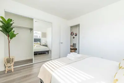 a white bedroom with a bed and a large mirror at Enjoy Alhambra Night Life at 2BR Apt in Alhambra
