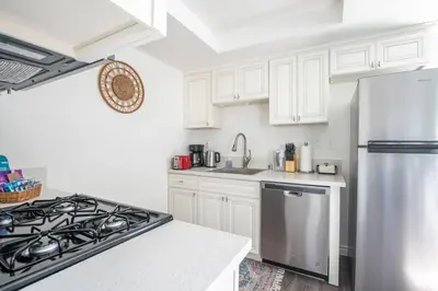 a kitchen with white cabinets and a stainless steel refrigerator at Enjoy Alhambra Night Life at 2BR Apt in Alhambra