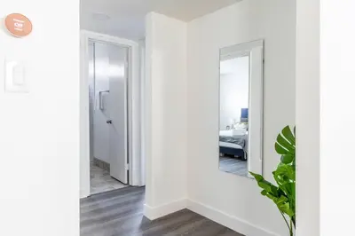 a hallway with white walls and a mirror at City Retreat Minutes to DT in Alhambra