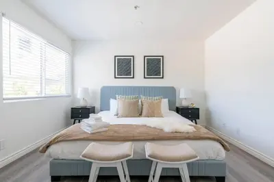 a white bedroom with a large bed with two chairs at Modern 2BR Condo with King Bed & Balcony near LA in Alhambra