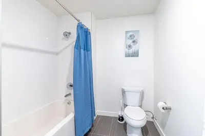 a bathroom with a toilet and a blue shower curtain at Hollywood Furnished Apartments in Los Angeles