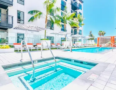 a pool with chairs and umbrellas next to a building at Hollywood Penthouse with Balcony & Pool View in Los Angeles