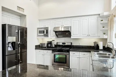 a kitchen with white cabinets and stainless steel appliances at Ultimate LA Vacation 2BR w Pool Above Shops in Monterey Park