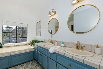 a bathroom with two sinks and two mirrors at North Shore Chalet Lake View, Spa and Game Rooms in Fawnskin