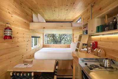 a small kitchen with a bed in a tiny house at Postcard Cabins Big Bear, Outdoor Collection by Marriott Bonvoy in Running Springs