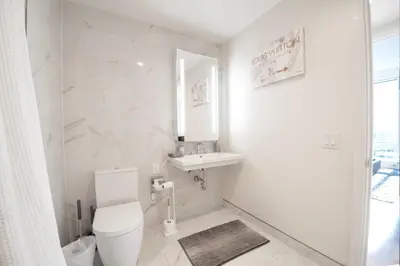 a white bathroom with a toilet and a sink at Lavish High-Rise 2bed Apt in the Hearth of Downtown LA in Los Angeles