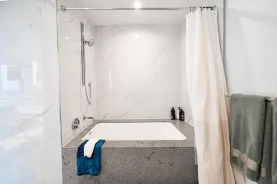 a bathroom with a tub and a shower with a shower curtain at Lavish High-Rise 2bed Apt in the Hearth of Downtown LA in Los Angeles