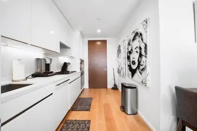 a kitchen with white cabinets and a trash can at Lavish High-Rise 2bed Apt in the Hearth of Downtown LA in Los Angeles