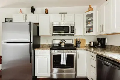 a kitchen with white cabinets and a stainless steel refrigerator at Blissful Bay Cabin in Big Bear Lake