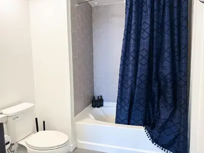 a bathroom with a toilet and a blue shower curtain at Modern Hollywood Home Sunset View & Free Parking - 10mins to Universal Studios in Los Angeles