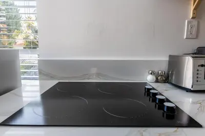 a black stove top in a kitchen with a microwave at Quiet King bed Westward Room in heart of Pasadena in Pasadena