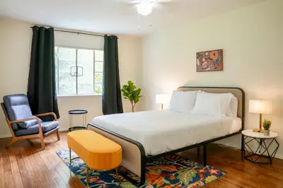 a bedroom with a bed and a chair and a window at Los Angeles Townhouse close to LACMA in Los Angeles