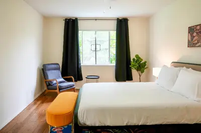 a bedroom with a bed and a chair and a window at Los Angeles Townhouse close to LACMA in Los Angeles