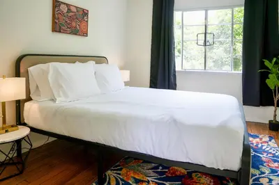 a bedroom with a bed with white sheets and a window at Los Angeles Townhouse close to LACMA in Los Angeles