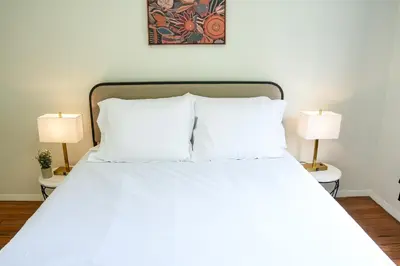 a bedroom with a white bed with two lamps at Los Angeles Townhouse close to LACMA in Los Angeles