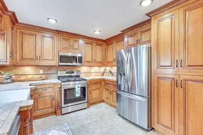 a kitchen with wooden cabinets and a stainless steel refrigerator at Redlands Home with Community Perks 1 Mi to Downtown in Redlands