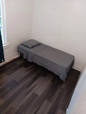 a small bed in a room with a wooden floor at House Downtown OC Santa Ana in Santa Ana