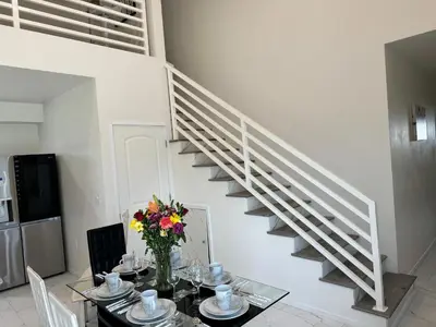 a dining room with a table and a staircase at Brand-New Dtla building with rooftop patio in Alhambra