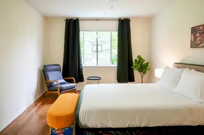 a bedroom with a bed and a chair and a window at Los Angeles Miracle Mile Spacious 2BR Townhouse in Los Angeles