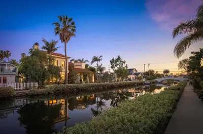 a canal with houses and palm trees next to a street at The Canal Escape - canal-front Italian villa in Los Angeles