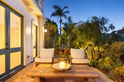 a patio with two white chairs and a wooden table at The Canal Escape - canal-front Italian villa in Los Angeles