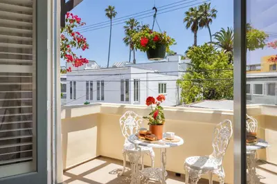 a balcony with a table and chairs and a view of a building at The Canal Escape - canal-front Italian villa in Los Angeles