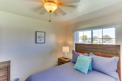 a bedroom with a bed with blue pillows and a window at Victorville Home with Large Yard and Charcoal Grill! in Victorville