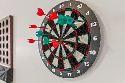 a dartboard on a wall with red darts at Los Angeles charming big house, king bed, parking, EV in Los Angeles