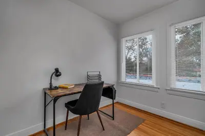 a desk with a chair in a room with windows at Chic Charming 2-Bedroom with office in the WeHo in Los Angeles