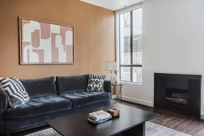 a living room with a black couch and a fireplace at Blueground Hollywood gym near Walk of Fame LAX-1217 in Los Angeles